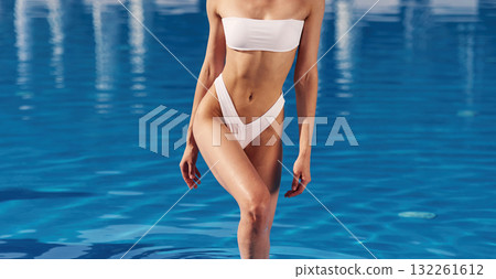 Fitness body type. Beautiful woman in bikini is resting by the pool 132261612