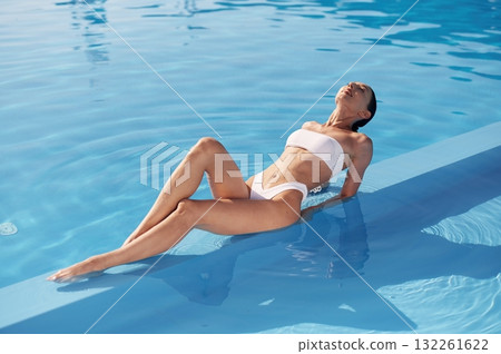 Lying down, close up view. Beautiful woman in bikini is resting by the pool 132261622