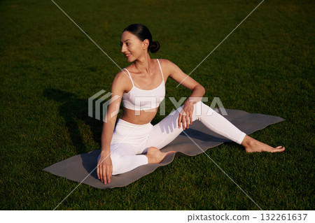 Taking a break. Attractive young fitness woman is on the green grass at daytime 132261637