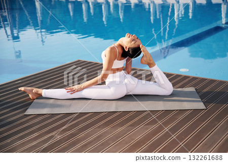 Doing twine. Fitness woman is near the pool Doing twine. Fitness woman is near the pool 132261688