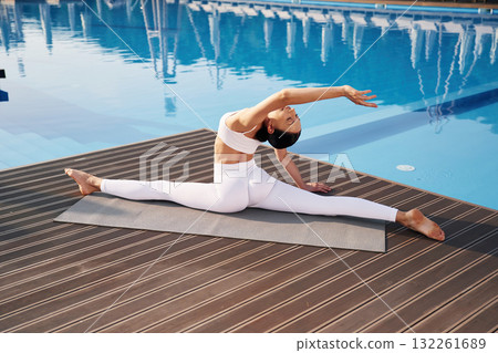 Clear water behind. Fitness woman is near the pool Clear water behind. Fitness woman is near the pool 132261689
