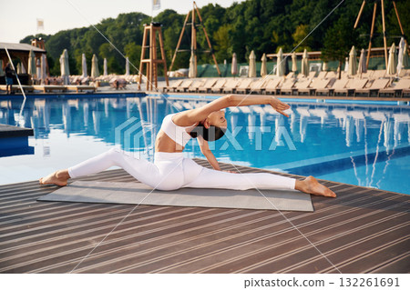 White clothes, side view, doing yoga. Fitness woman is near the pool 132261691