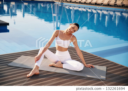 Clear water behind. Fitness woman is near the pool Clear water behind. Fitness woman is near the pool 132261694