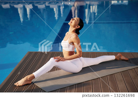 Doing twine. Fitness woman is near the pool Doing twine. Fitness woman is near the pool 132261698