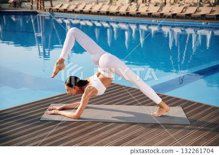 White clothes, side view, doing yoga. Fitness woman is near the pool 132261704