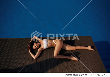 Near the water, rest. Beautiful woman in bikini is resting by the pool Near the water, rest. Beautiful woman in bikini is resting by the pool 132261742