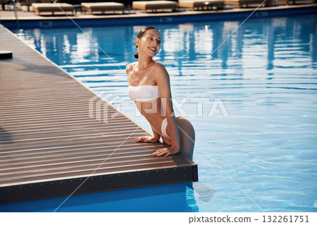 Positive vibes. Beautiful woman in bikini is resting by the pool Positive vibes. Beautiful woman in bikini is resting by the pool 132261751