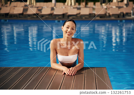 Positive vibes. Beautiful woman in bikini is resting by the pool Positive vibes. Beautiful woman in bikini is resting by the pool 132261753