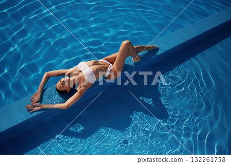 View from the top, lying down. Beautiful woman in bikini is resting by the pool View from the top, lying down. Beautiful woman in bikini is resting by the pool 132261758