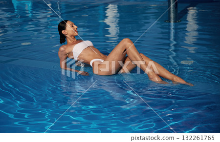 Fresh and clean water. Beautiful woman in bikini is resting by the pool 132261765