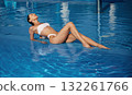 Chill time, clear water. Beautiful woman in bikini is resting by the pool 132261766