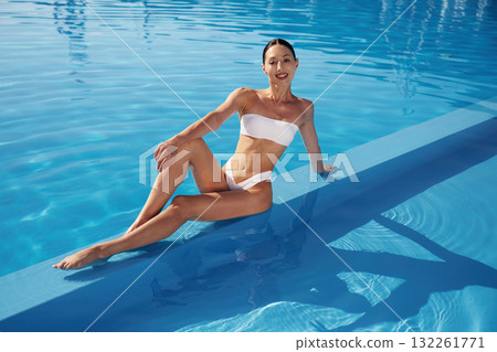 Conception of wellness. Beautiful woman in bikini is resting by the pool 132261771
