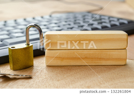 A bright brass padlock positioned on a desk near a computer keyboard with blank wooden blocks with customizable space for text. 132261804