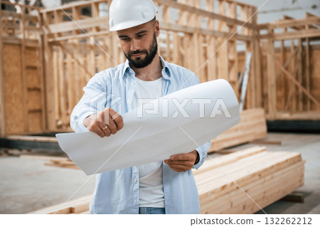 Architect is with plan of the building. Industrial worker in wooden warehouse 132262212