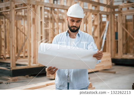 Architect is with plan of the building. Industrial worker in wooden warehouse 132262213