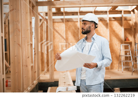 Architect is with plan of the building. Industrial worker in wooden warehouse Architect is with plan of the building. Industrial worker in wooden warehouse 132262219