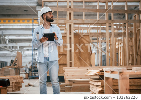Unfinished project, holding digital tablet. Industrial worker in wooden warehouse Unfinished project, holding digital tablet. Industrial worker in wooden warehouse 132262226