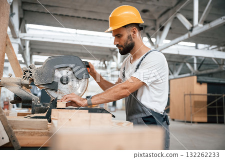 Side view, cutting the wood. Industrial worker in the warehouse 132262233