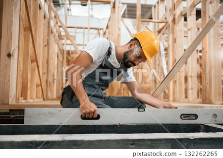 Checking the straight by using leveling tool. Industrial worker in wooden warehouse Checking the straight by using leveling tool. Industrial worker in wooden warehouse 132262265