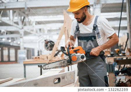 With saw. Industrial worker in wooden warehouse With saw. Industrial worker in wooden warehouse 132262289