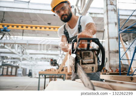 Saw in hands. Industrial worker in wooden warehouse Saw in hands. Industrial worker in wooden warehouse 132262299