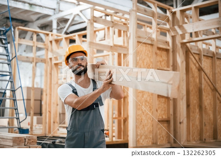 Going and carrying plank. Industrial worker in wooden warehouse 132262305