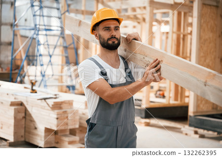 Front view, holding plank. Industrial worker in wooden warehouse 132262395