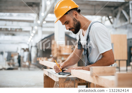 Yellow pen, marks the area. Industrial worker in wooden warehouse 132262414