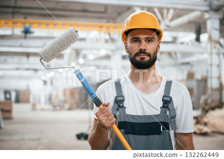 With brush for coloring. Industrial worker in wooden warehouse 132262449