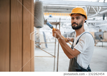 With brush for coloring. Industrial worker in wooden warehouse 132262454