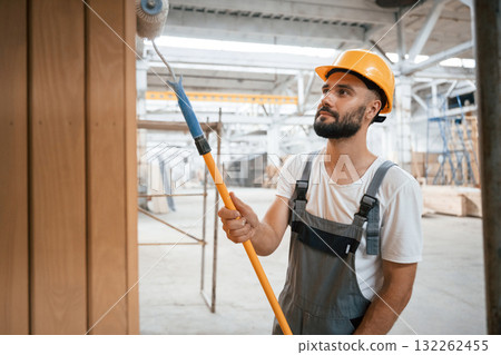 With brush for coloring. Industrial worker in wooden warehouse With brush for coloring. Industrial worker in wooden warehouse 132262455