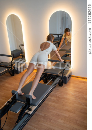 Pilates Woman showcases deep hamstring stretch, reformer exercise emphasizing hamstrings and breath control 132262636