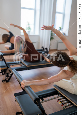 Pilates group of Women doing mermaid exercise in a sunlite modern studio, embodying calm, focus, and strength. Pilates group of Women doing mermaid exercise in a sunlite modern studio, embodying calm, focus, and strength. 132262653