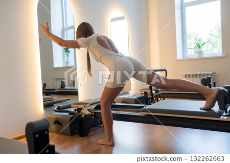 Woman training pilates on the reformer bed. Reformer pilates studio machine for fitness workouts in gym. Fit, healthy and strong authentical body. Fitness concept Woman training pilates on the reformer bed. Reformer pilates studio machine for fitness workouts in gym. Fit, healthy and strong authentical body. Fitness concept 132262663