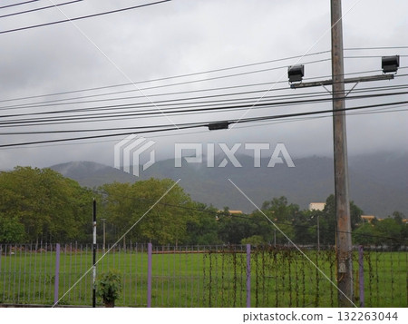 Misty Field with Purple Fencing and Distant Mountains Under Cloudy Skies 132263044