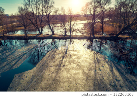 Aerial view of the countryside and frozen creek with a dam in the evening under sunset light. Beautiful natural landscape Aerial view of the countryside and frozen creek with a dam in the evening under sunset light. Beautiful natural landscape 132263103