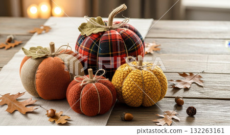 Handmade fabric and knit pumpkins on a rustic wooden table with autumn leaves and acorns. Fall decor. 132263161