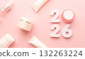 Best skincare products and cosmetic trends of 2026 concept. 2026 white number with lip balm, cream bottle, serum and lotion on pink background. 132263224