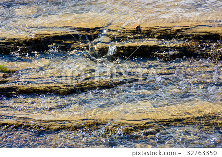 nature texture with stones in the water steam. closeup background of a river shore in autumn nature texture with stones in the water steam. closeup background of a river shore in autumn 132263350
