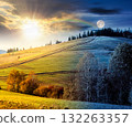 forest on grassy hill on autumn equinox. day and night time change concept. beautiful rural scenery with rolling pasture. mountainous countryside with sun and moon at twilight. warm october weather 132263357