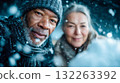 Elderly couple smiling outdoors during snowfall on a winter day 132263392