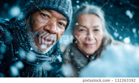 Elderly couple smiling outdoors during snowfall on a winter day Elderly couple smiling outdoors during snowfall on a winter day 132263392