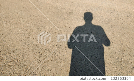 Shadow of a man on empty road in daylight symbolizing solitude journey identity and reflection in minimal urban scene 132263394