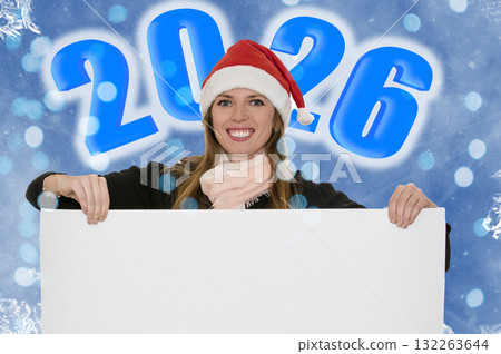Young woman wearing a Santa hat holding sheet of paper. 2026 inscription. 132263644