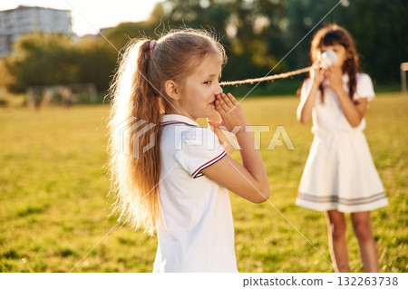 Using tin can telephone. Happy kids are on the summer field Using tin can telephone. Happy kids are on the summer field 132263738