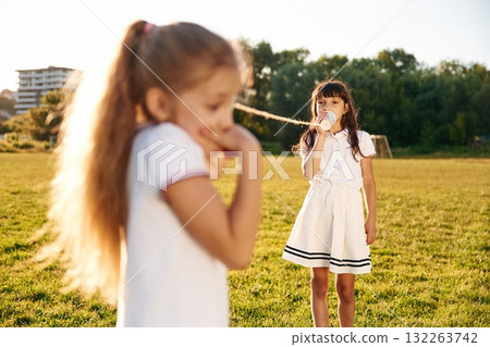 Fun, with tin can phone. Happy kids are on the summer field Fun, with tin can phone. Happy kids are on the summer field 132263742