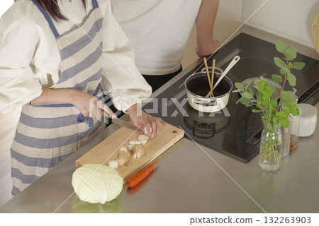 一名男子正與一名繫著圍裙做飯的女子愉快地交談 132263903