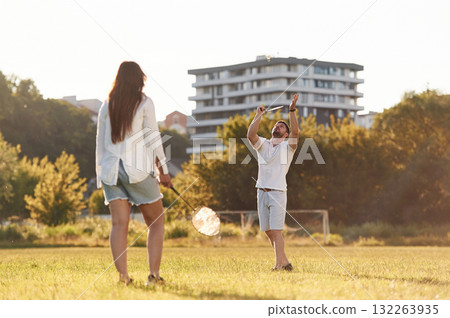 Conception of sports and hobby. Man with woman are playing badminton on the field Conception of sports and hobby. Man with woman are playing badminton on the field 132263935
