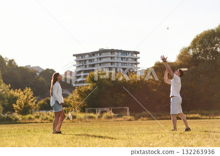 Side view. Man with woman are playing badminton on the field 132263936