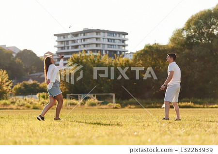 Side view. Man with woman are playing badminton on the field Side view. Man with woman are playing badminton on the field 132263939